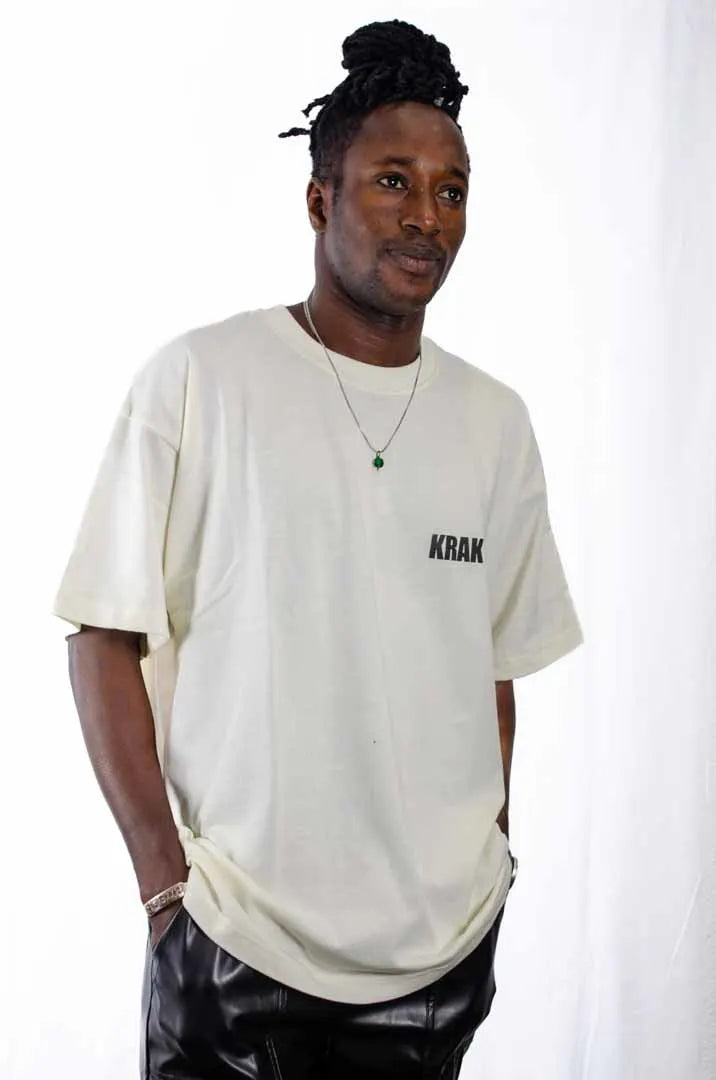 Modelo hombre vistiendo la Camiseta Mac Miller. Camiseta streetwear oversized con hombros caídos. Algodón 100% orgánico en color Leche de coco.