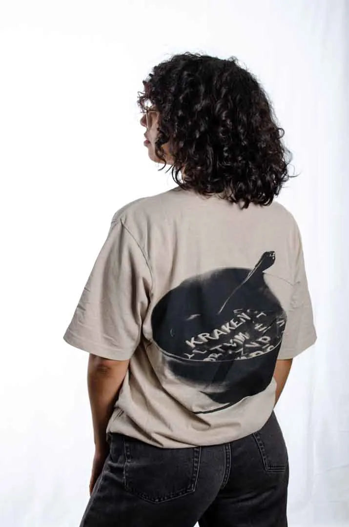 Vista lateral de una modelo mujer vistiendo la Camiseta Sancocho. Camiseta streetwear oversized efecto lavado en color gris ciudad, confeccionada en 100% algodón orgánico.