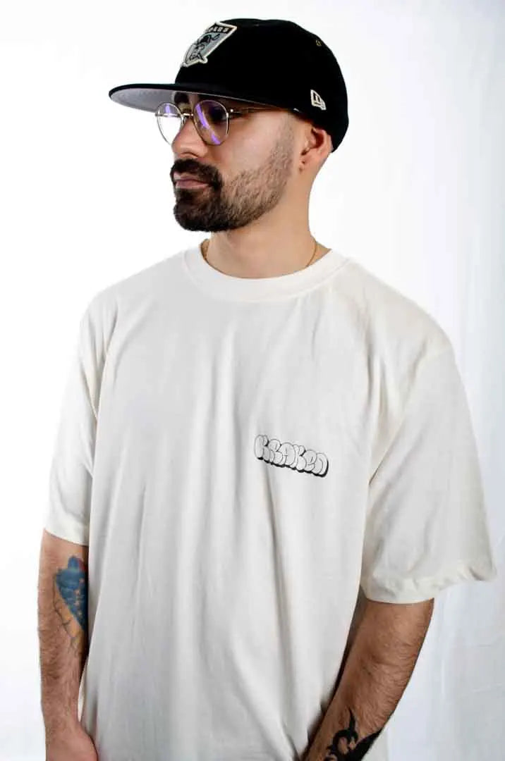 Modelo hombre vistiendo la Camiseta Las Brujas. Camiseta streetwear oversized color Leche de coco, fabricada con algodón 100% orgánico.