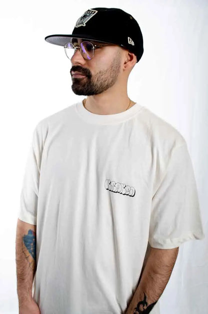 Modelo hombre vistiendo la Camiseta Las Brujas. Camiseta streetwear oversized color Leche de coco, fabricada con algodón 100% orgánico.