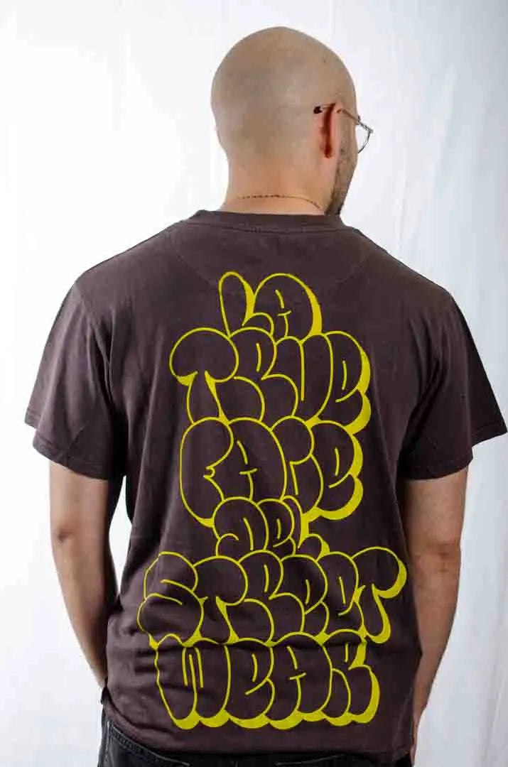 Vista trasera de un modelo hombre vistiendo la Camiseta La True Face. Camiseta streetwear oversized efecto lavado en color café americano, de algodón orgánico.