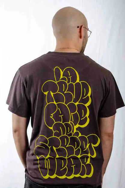 Vista trasera de un modelo hombre vistiendo la Camiseta La True Face. Camiseta streetwear oversized efecto lavado en color café americano, de algodón orgánico.