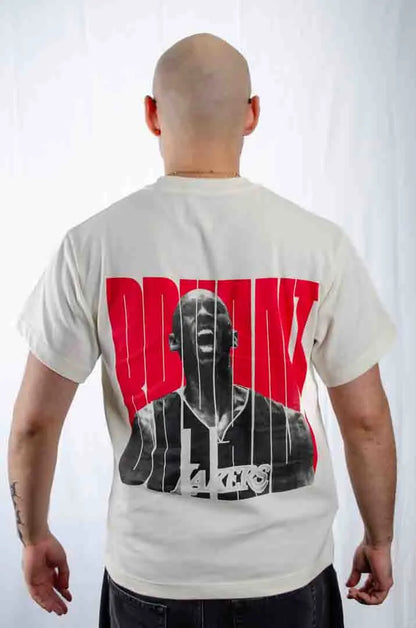 Vista trasera de un modelo hombre vistiendo la Camiseta Kobe Bryant. Camiseta streetwear oversized con hombros caídos, de algodón 100% orgánico en color Leche de coco.