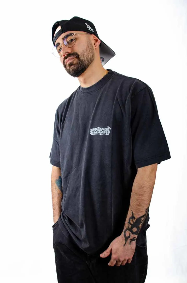 Vista lateral de un modelo hombre vistiendo la Camiseta Tu tío Paco. Camiseta streetwear oversized efecto lavado en color negro, hecha con algodón 100% orgánico.