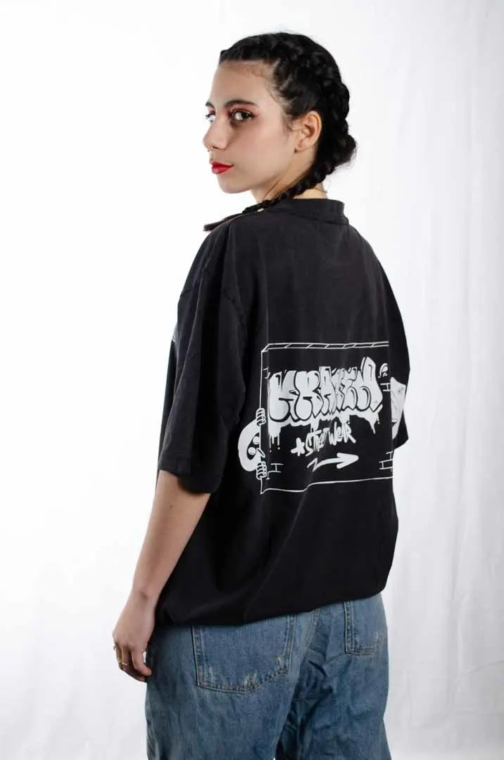 Vista lateral de una modelo mujer vistiendo la Camiseta Tu tío Paco. Camiseta streetwear oversized efecto lavado en color negro, hecha con algodón 100% orgánico.