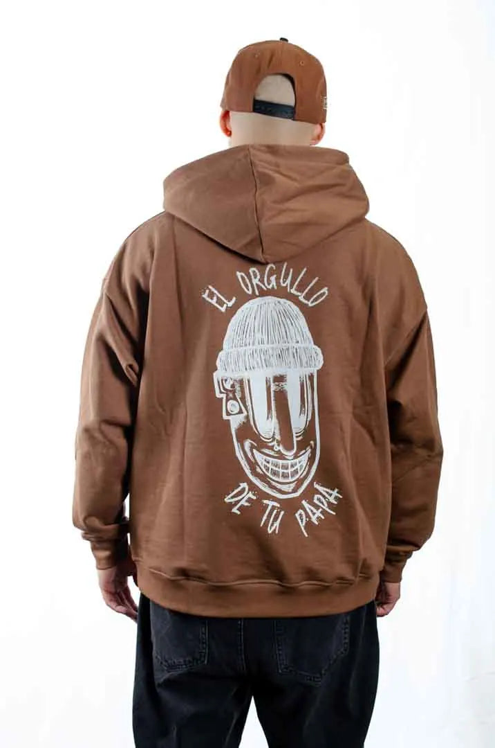 Vista trasera de un modelo hombre vistiendo la Sudadera El Orgullo de tu Papá con capucha puesta. Sudadera streetwear oversized en color Brownie especial y fabricada con material de felpa perchada 100% algodón.