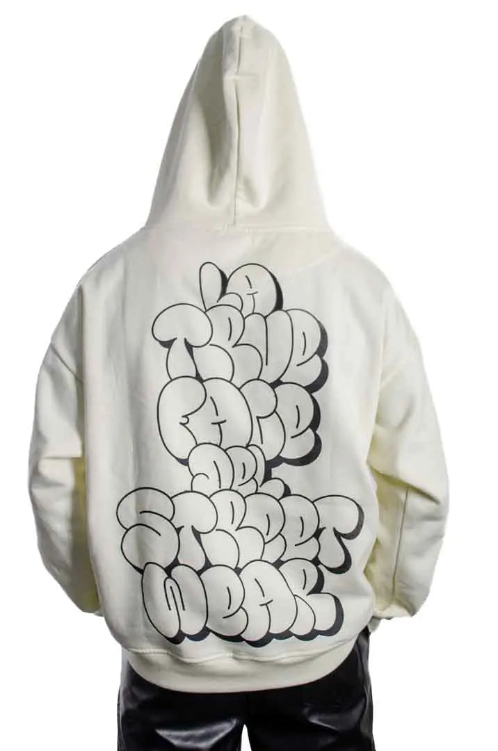 Vista trasera de un modelo hombre vistiendo la Sudadera La True Face con capucha puesta. Sudadera hoodie oversized, 100% algodón felpa en color Leche de coco.