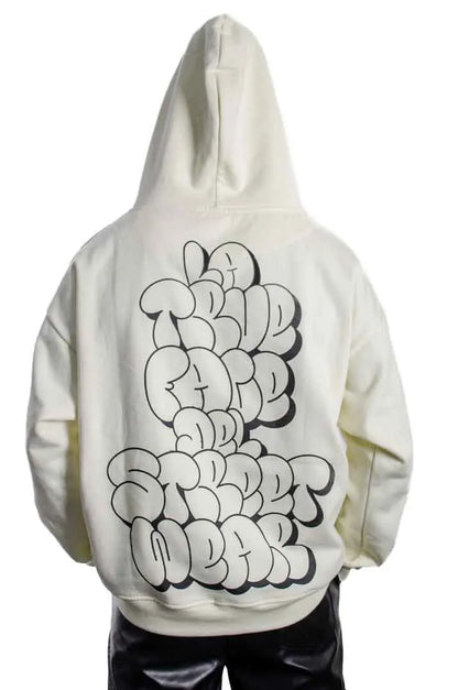 Vista trasera de un modelo hombre vistiendo la Sudadera La True Face con capucha puesta. Sudadera hoodie oversized, 100% algodón felpa en color Leche de coco.