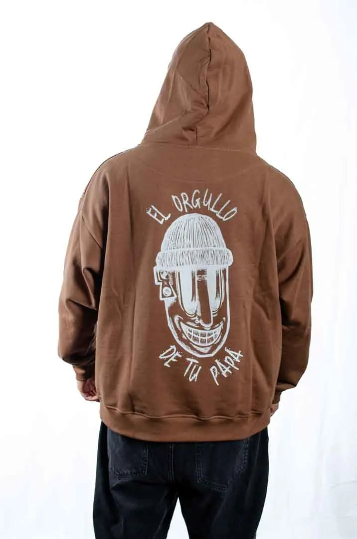 Vista trasera de un modelo hombre vistiendo la Sudadera El Orgullo de tu Papá con capucha puesta. Sudadera streetwear oversized en color Brownie especial y fabricada con material de felpa perchada 100% algodón.