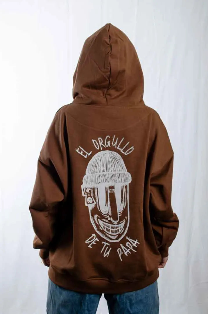 Vista trasera de una modelo mujer vistiendo la Sudadera El Orgullo de tu Papá con capucha puesta. Sudadera streetwear oversized en color Brownie especial y fabricada con material de felpa perchada 100% algodón.