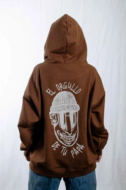 Vista trasera de una modelo mujer vistiendo la Sudadera El Orgullo de tu Papá con capucha puesta. Sudadera streetwear oversized en color Brownie especial y fabricada con material de felpa perchada 100% algodón.