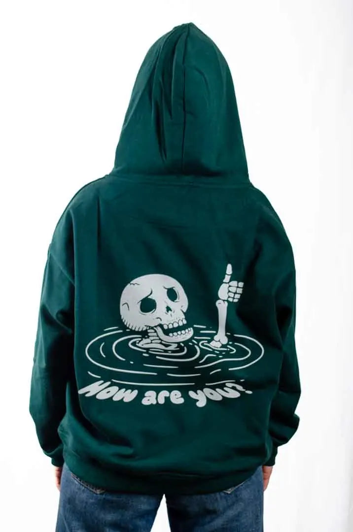 Vista trasera de una modelo mujer vistiendo la Sudadera Keloke con capucha puesta. Sudadera streetwear oversized, en color verde solera y fabricada con material de felpa perchada 100% algodón.