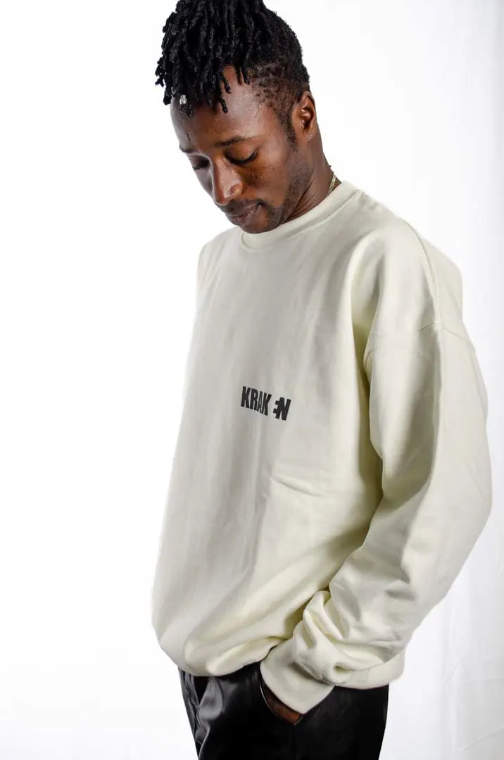 Vista lateral de un modelo hombre vistiendo la Sudadera Sancocho. Sudadera brushed oversized sin capucha, de felpa perchada 100% algodón en color Leche de coco.