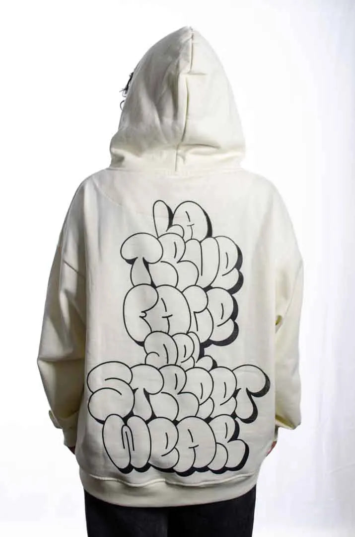 Vista trasera de un modelo hombre vistiendo la Sudadera La True Face con capucha puesta. Sudadera hoodie oversized, 100% algodón felpa en color Leche de coco.