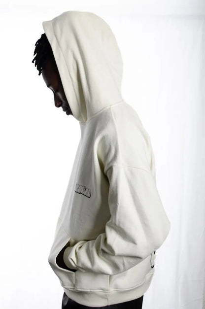Vista lateral de un modelo hombre vistiendo la Sudadera La True Face. Sudadera hoodie oversized con capucha, 100% algodón felpa en color Leche de coco.
