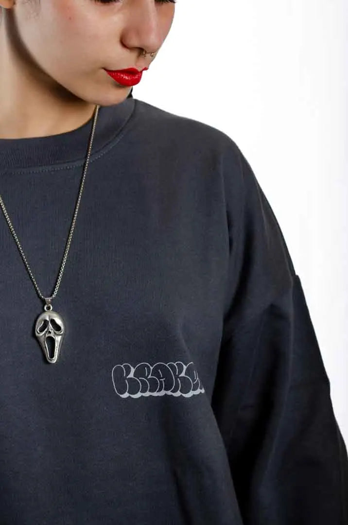 Detalle del logo Kraken en la Sudadera La Brujas. Sudadera streetwear oversized sin capucha, de felpa perchada 100% algodón en color Gris Lobo.
