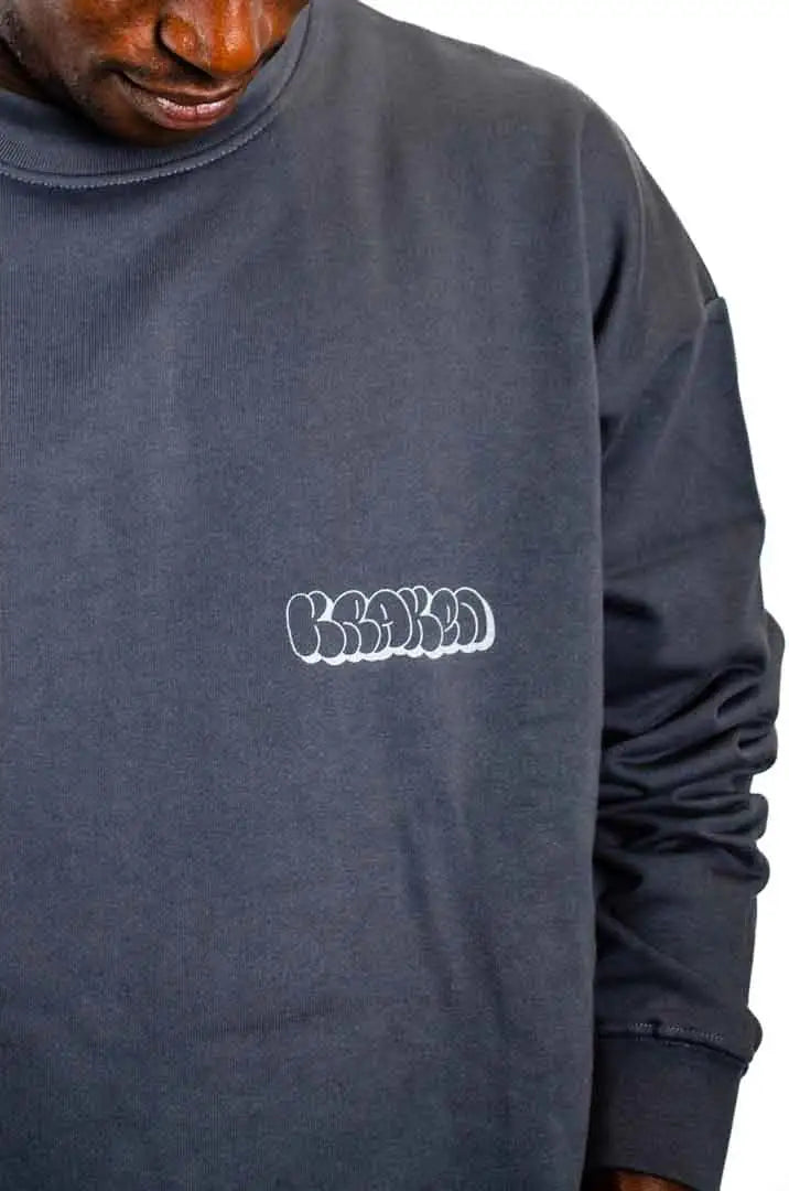 Detalle del logo Kraken en la Sudadera La Brujas. Sudadera streetwear oversized sin capucha, de felpa perchada 100% algodón en color Gris Lobo.