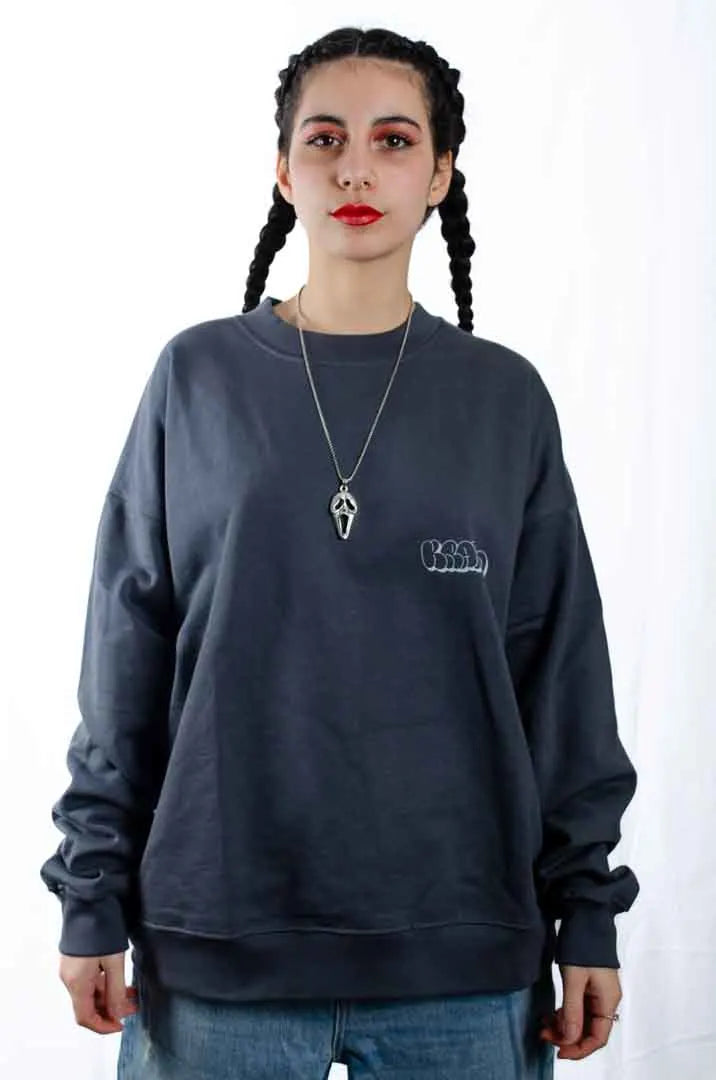 Modelo mujer vistiendo la Sudadera La Brujas. Sudadera streetwear oversized sin capucha, de felpa perchada 100% algodón en color Gris Lobo.
