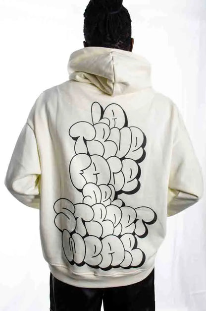 Vista trasera de un modelo hombre vistiendo la Sudadera La True Face. Sudadera hoodie oversized con capucha, 100% algodón felpa en color Leche de coco.